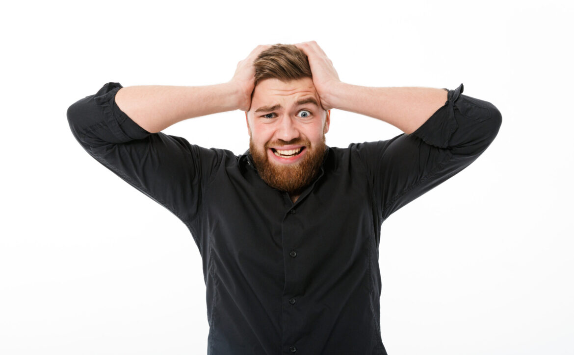 Worried bearded man in shirt holding his head