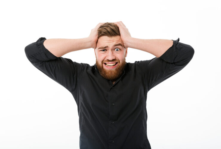 Worried bearded man in shirt holding his head